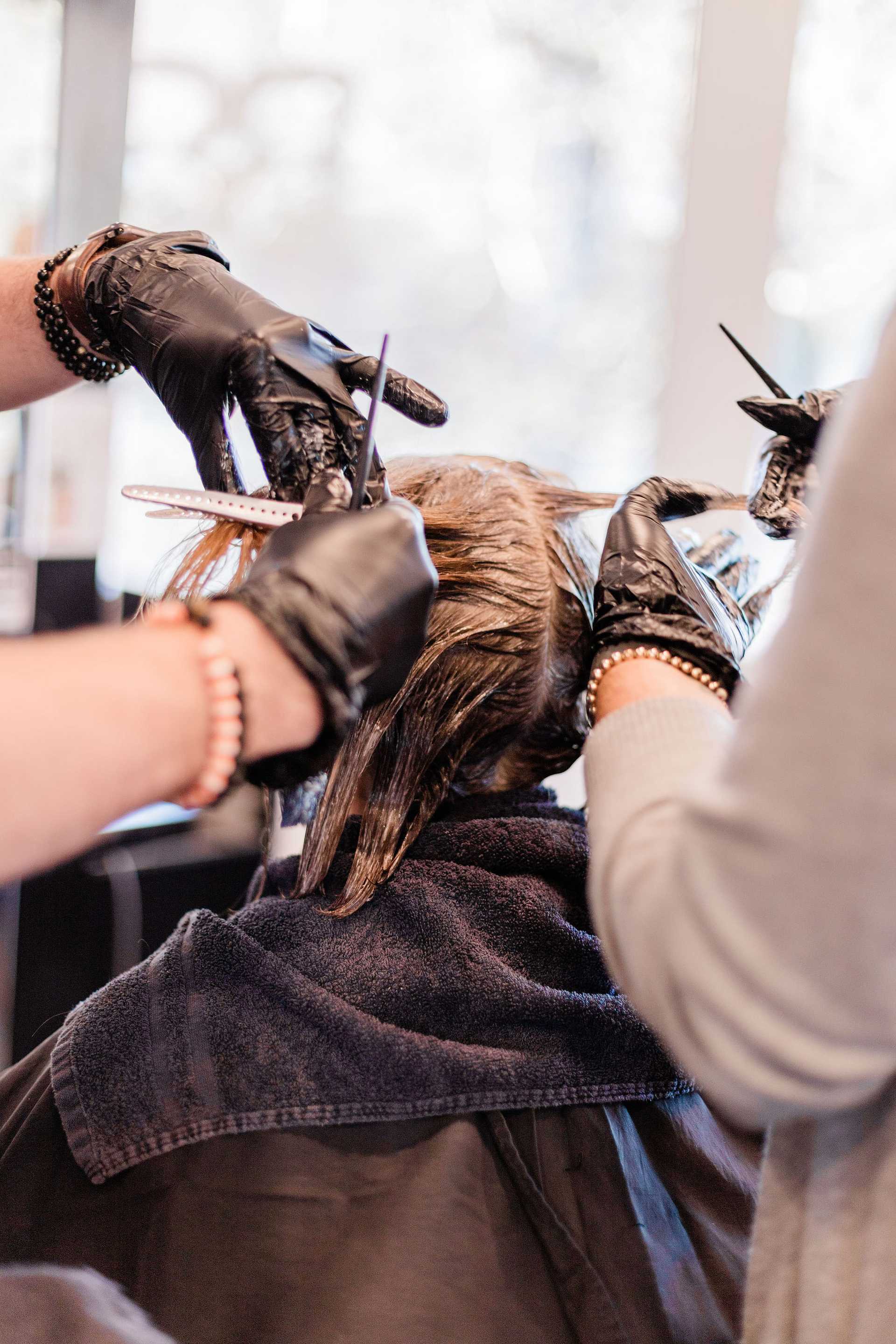 Hairdresser applying color to a client's hair in a salon.