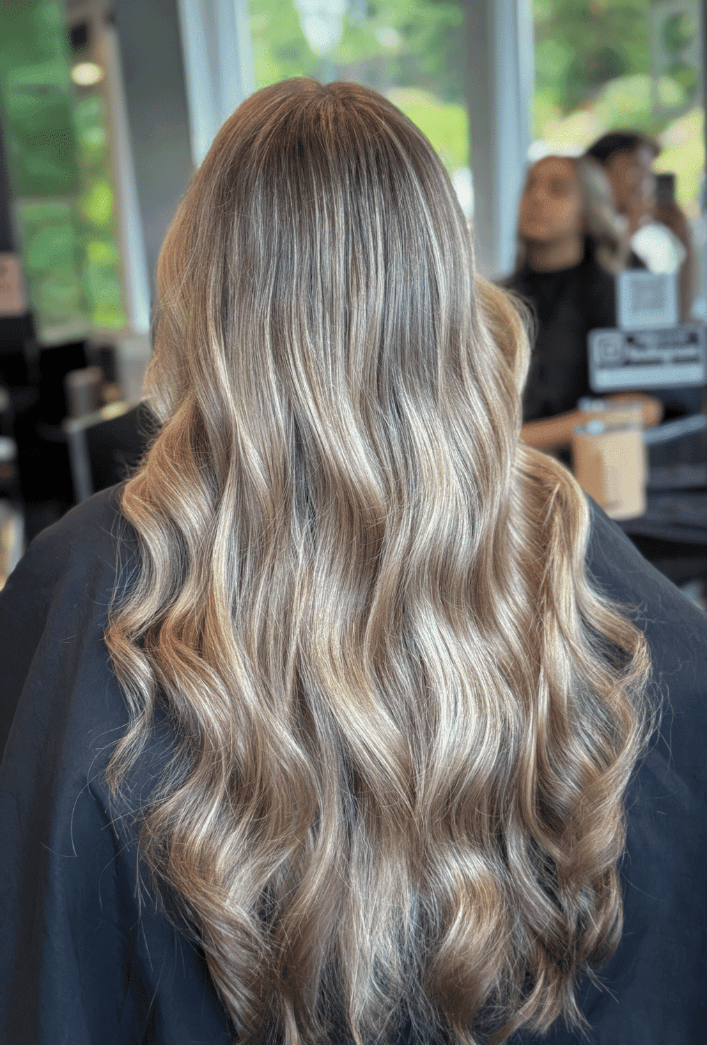 Long wavy blonde hair flowing down a person's back in a salon.