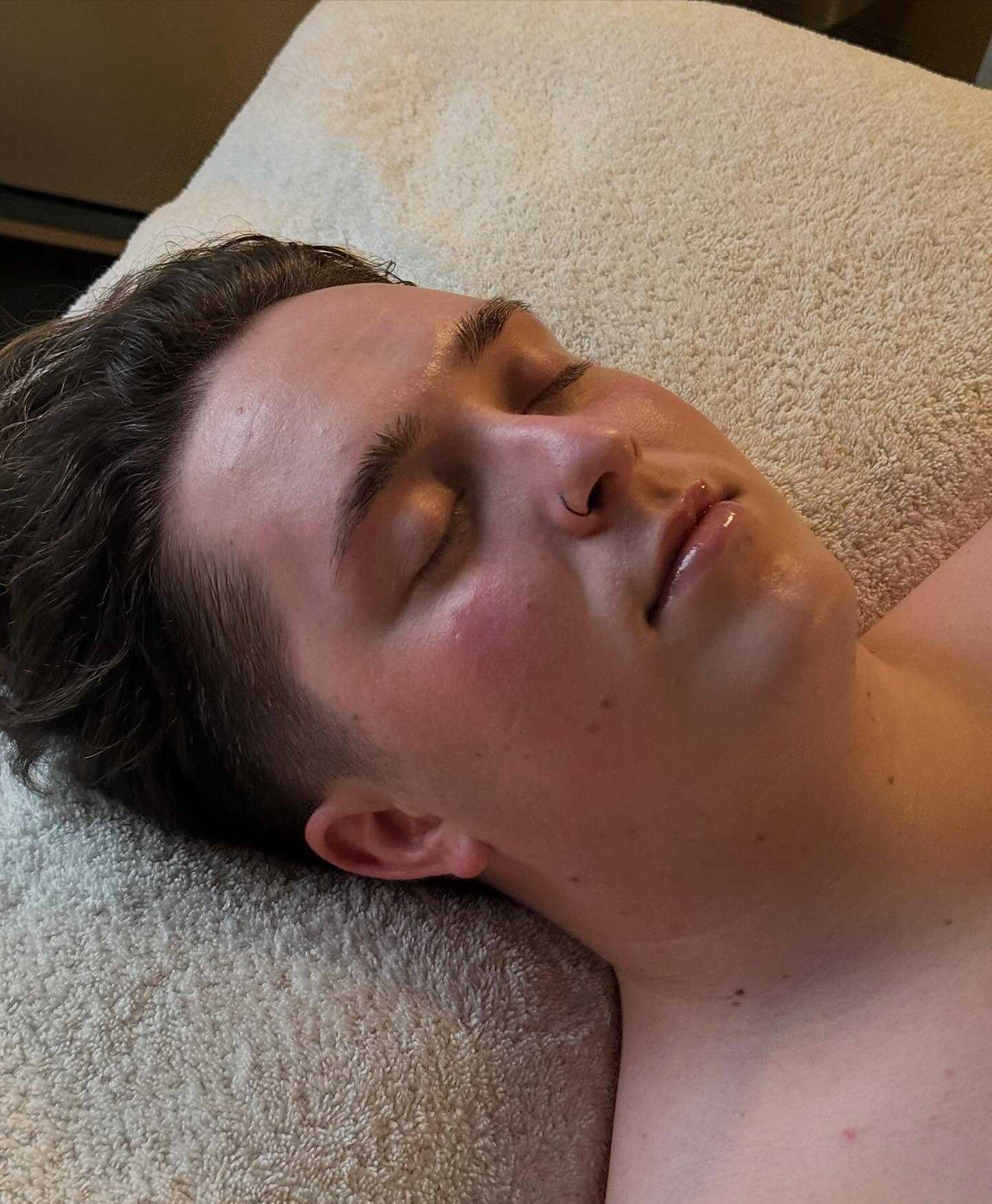 Person relaxing on a spa bed, eyes closed, enjoying a facial treatment.