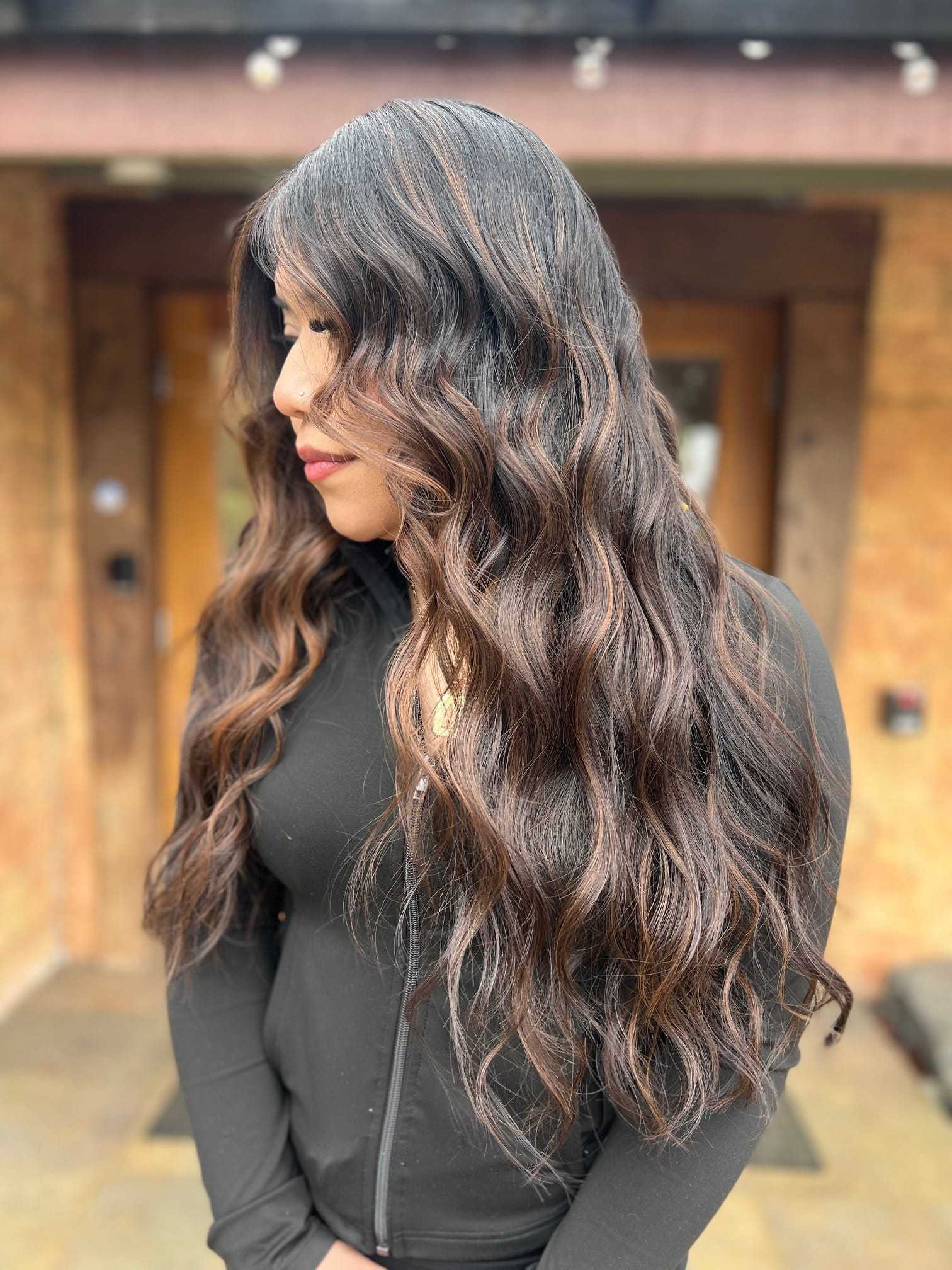 Woman with long, wavy hair standing in front of a wooden door.
