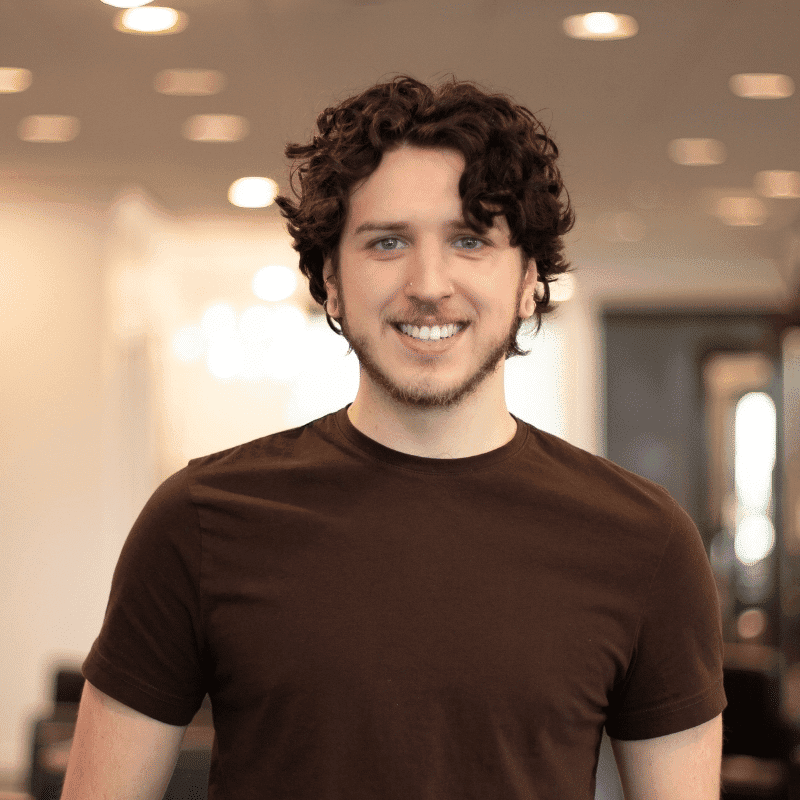 Portrait of Conrad, a professional stylist at Brassfields Salon and Day Spa, showcasing their expertise and style.