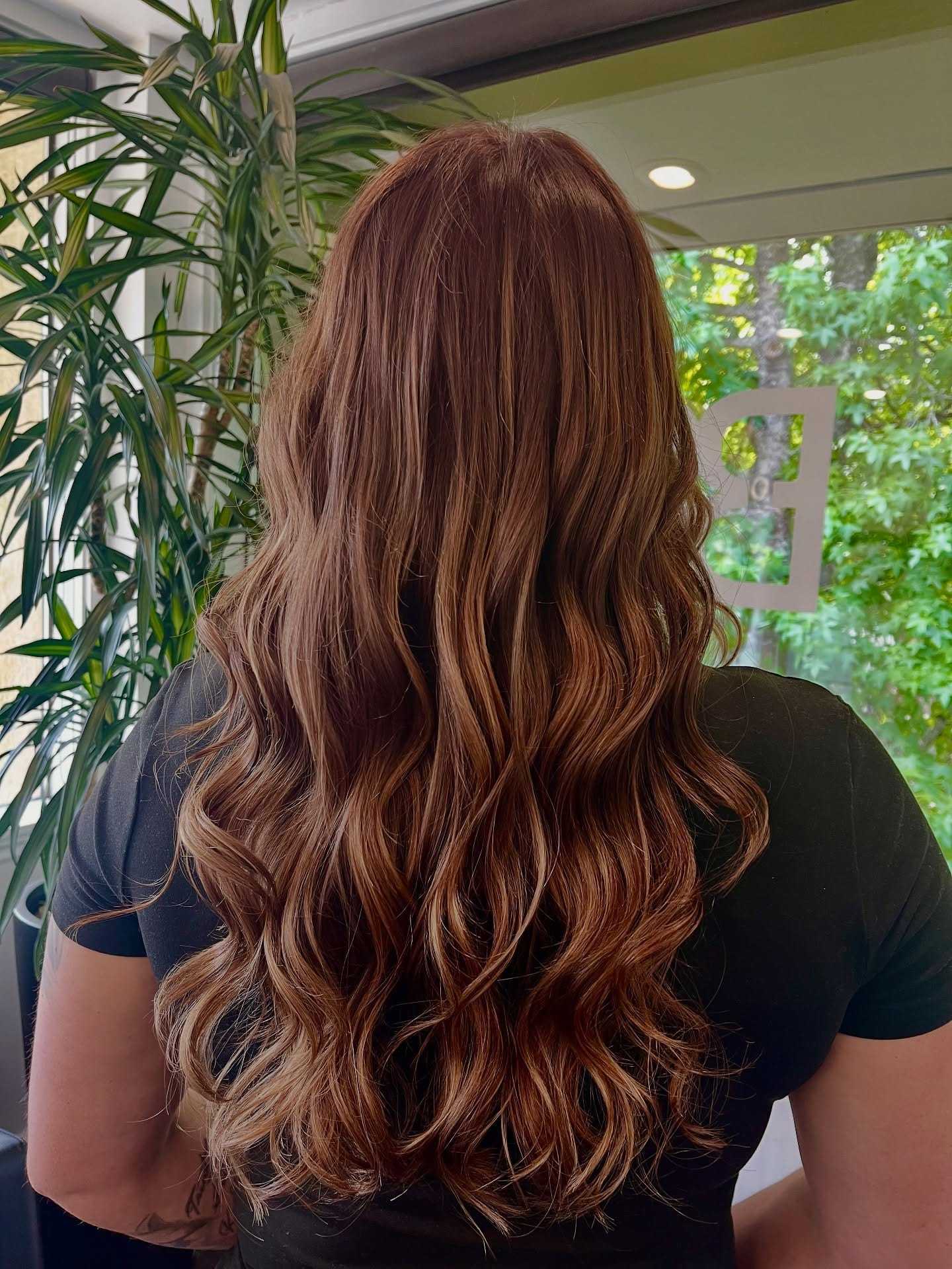 Wavy brown hair cascading down a woman's back in a salon setting.